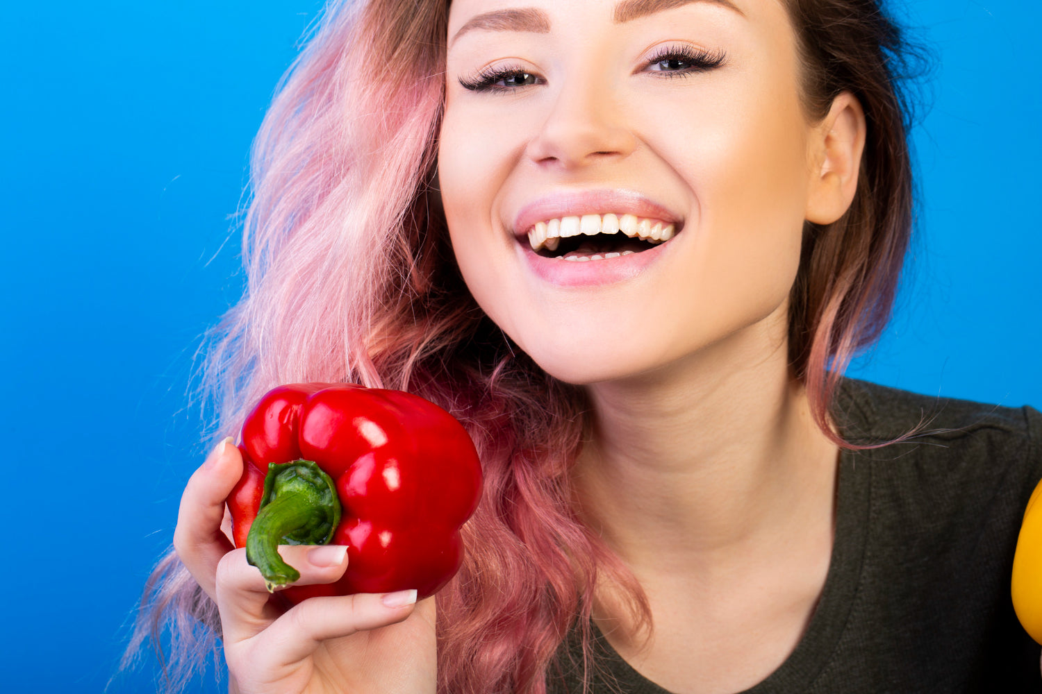 Eine lächelnde Frau mit weißen Zähnen und einer Paprika in der Hand