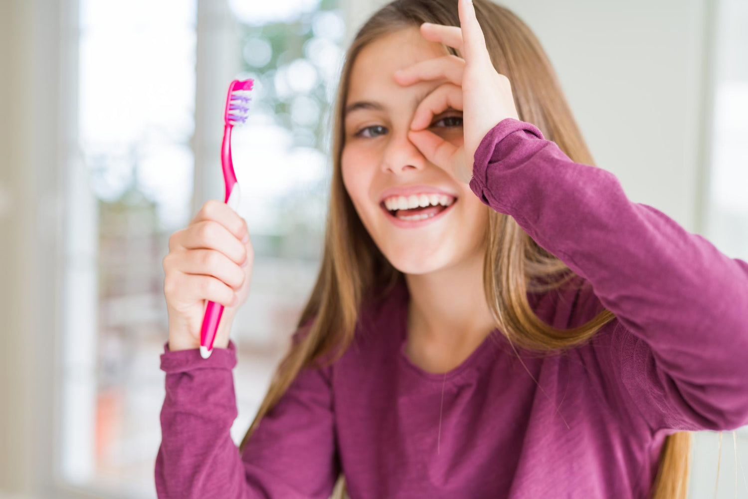 Junges lächelndes Mädchen mit pinken Zahnbürste in der Hand