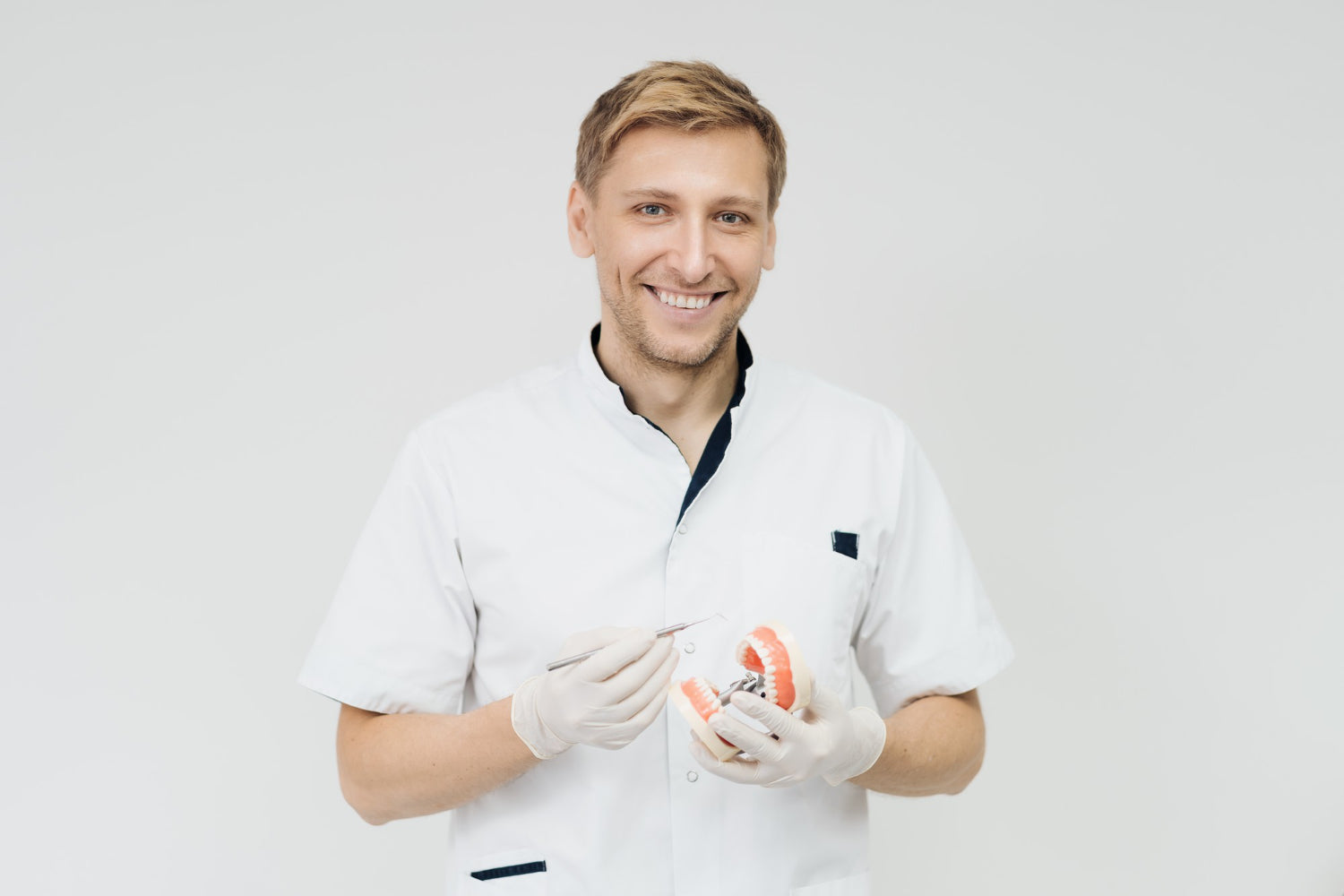 Zahnarzt mit Zahnsonde und Kiefermodell in den Händen