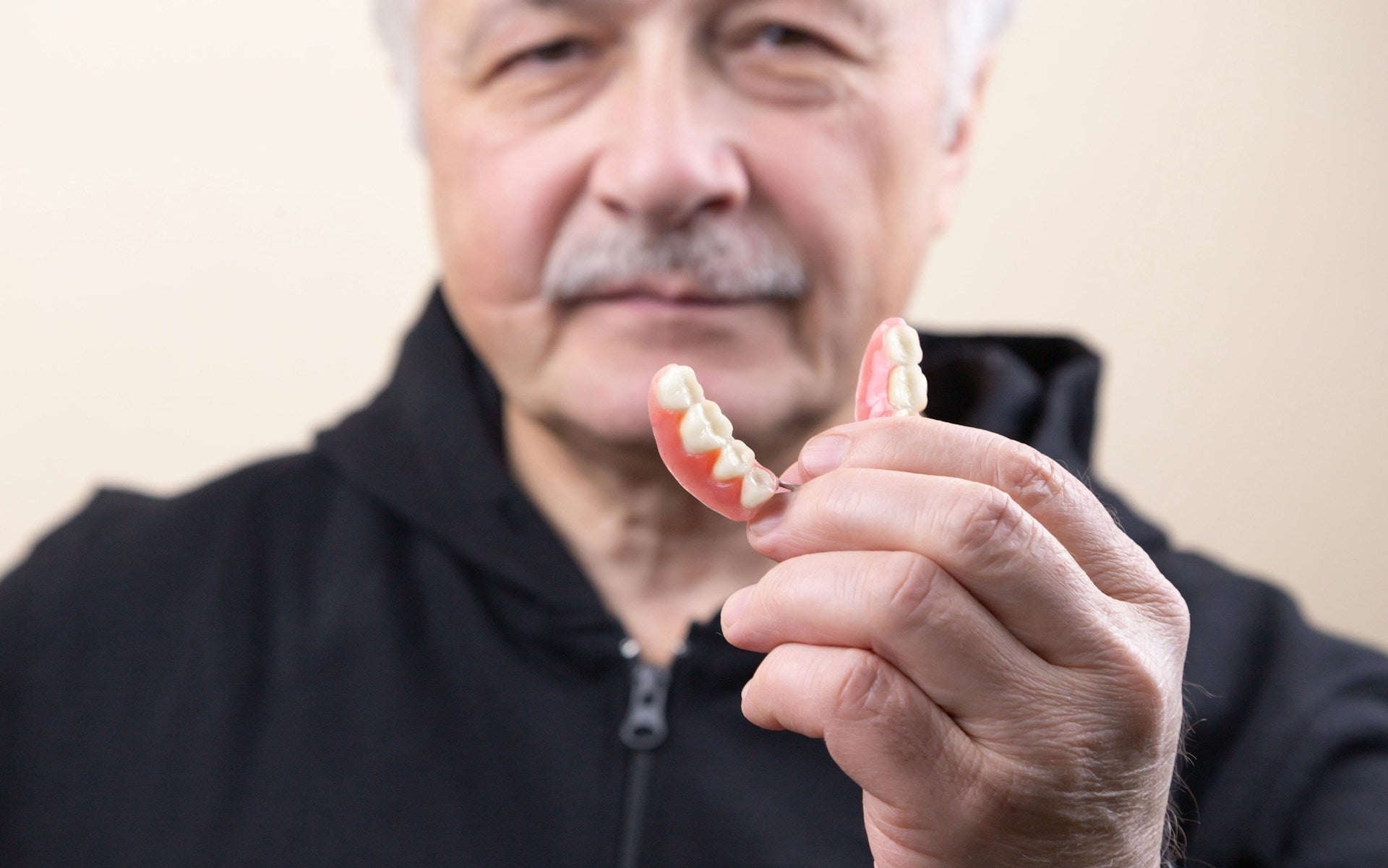 Älterer Herr mit Zahnersatz in der Hand